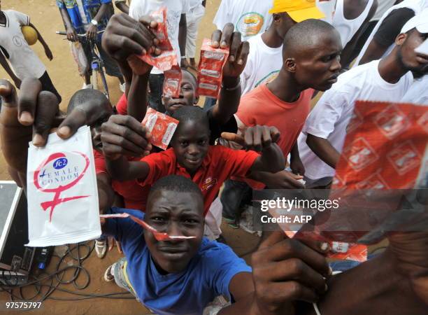 Youngsters brandish condoms, they received in Yopougon, a working district of the capital city Abidjan on September 28 as part of an AIDS prevention...