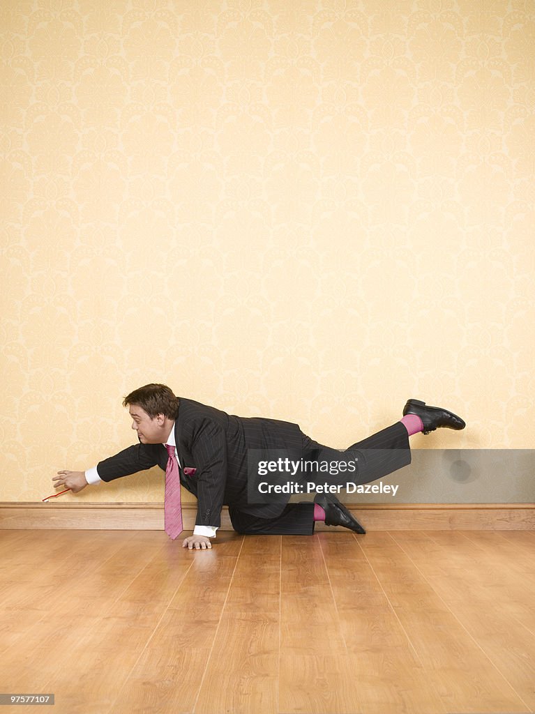 Man cleaning skirting board with toothbrush
