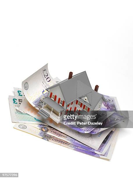 house balanced on stack of pound notes - sold engels woord stockfoto's en -beelden
