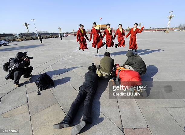 Photographers take pictures of Chinese hostesses jumping as they pose for pictures on the Tiananmen Square during a plenary session of the National...