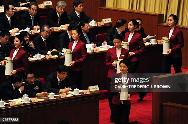 Hostesses take to the stage to refill the teacups of top leaders at the Great Hall of the People in Beijing on March 9, 2010 during an ongoing...