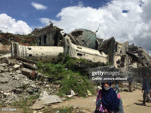 May 2018, Philippines, Marawi: A woman walks in front of a toppled mosque in ground zero, or the main battle area, in Marawi City in the southern...