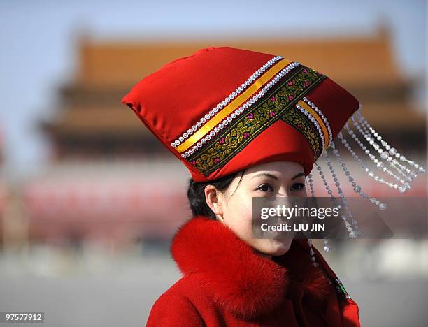 Hostesses dressed in the costume of an ethinic minoritiy pose for souvenir pictures on Tiananmen Square during a plenary session of the National...