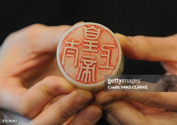 An expert holds a white jade seal of the 'Taishang huangdi' series estimated to fetch 6.4 million US dollars at auction, during a press preview of...