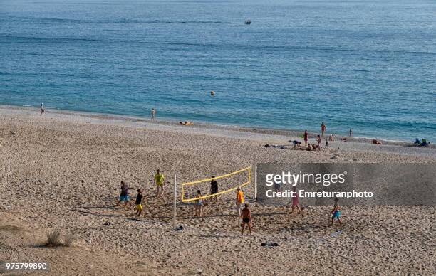 people playing beach volley on sand near the sea. - emreturanphoto foto e immagini stock
