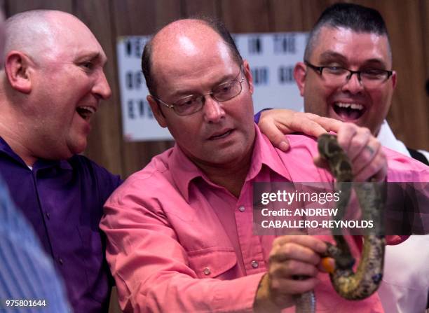Pastor Chris Wolford , and Randy Brandon smile as pastor David Culberston holds a tiber rattlesnake during a Pentecostal serpent handlers service at...