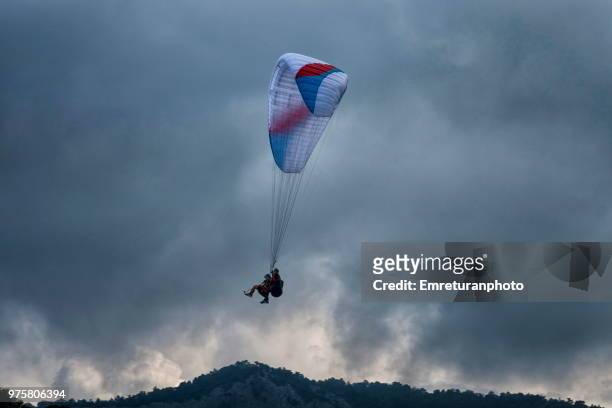 para glider coming down on an overcast day at ölüdeniz,fethiye. - emreturanphoto stock pictures, royalty-free photos & images