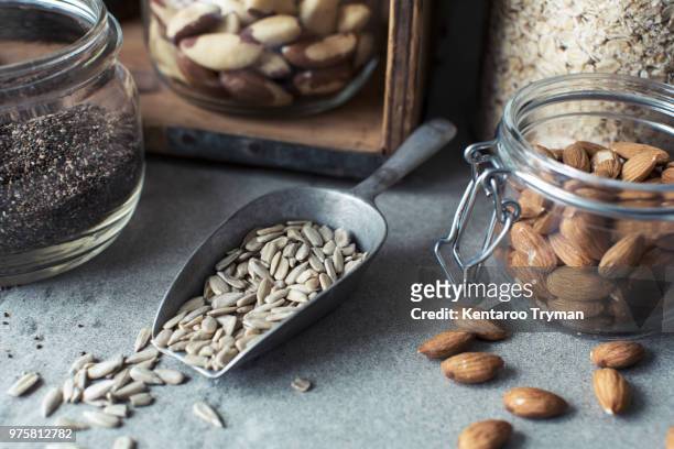 close-up of seeds in serving scoop with almonds in jar on kitchen counter - close up counter ストックフォトと画像