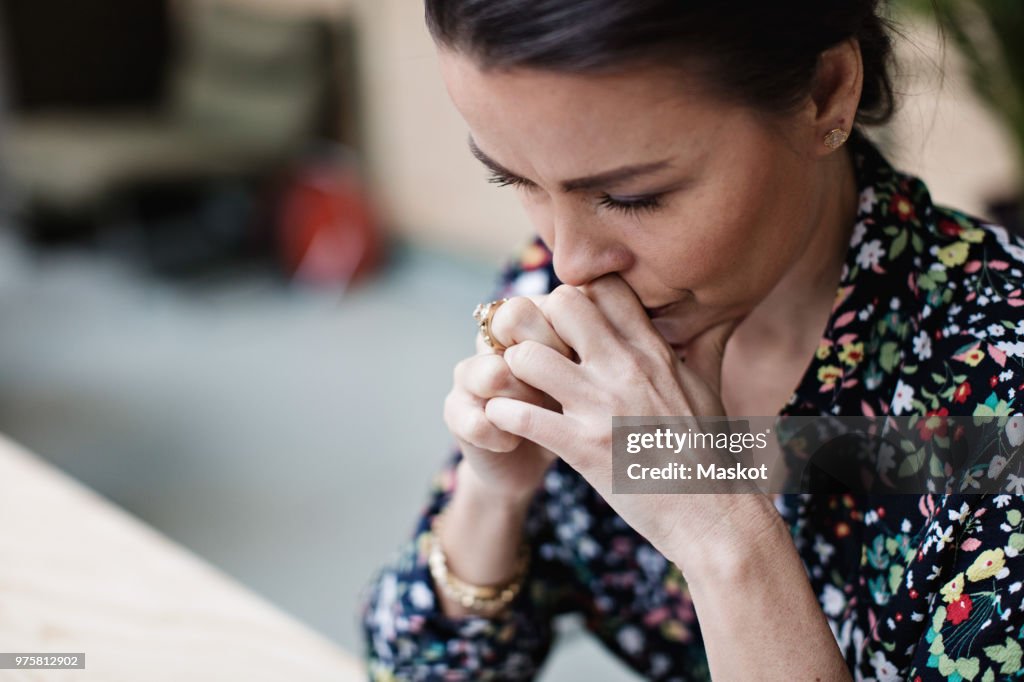 Close-up of tired thoughtful businesswoman with arms crossed at office