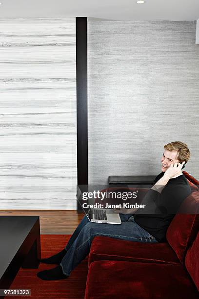 young man with laptop talking on cell phone. - dartmouth nova scotia stock-fotos und bilder