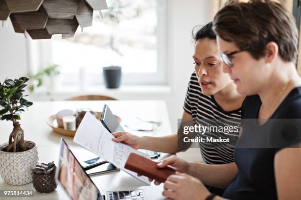 lesbian couple discussing over financial bills while using laptop at table - lgbt mobile foto e immagini stock