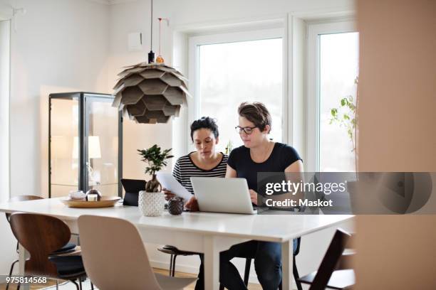 lesbian couple discussing financial bills over laptop while sitting at table - home insurance stock pictures, royalty-free photos & images