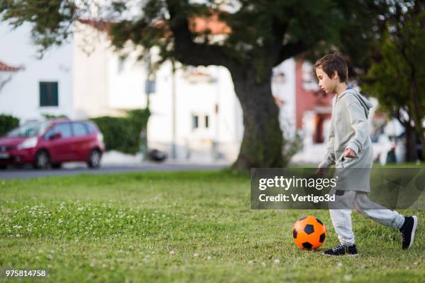 junge mit fußball spielen - street football stock-fotos und bilder