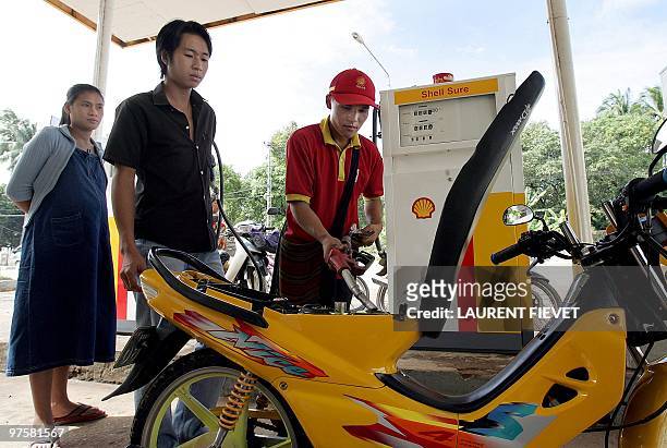 Couple have their scooter filled up by a gas station attendant, in Vientiane 27 July 2005. Oil prices were lower in Asian trade amid expectations the...