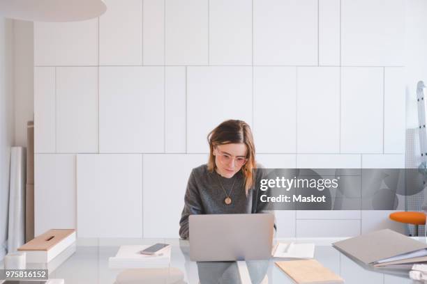 young female entrepreneur using laptop at desk in workshop - desk front view stock pictures, royalty-free photos & images