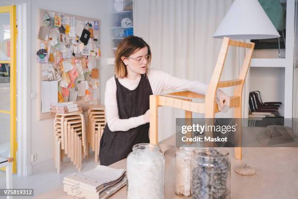 young female upholstery worker working on chair in workshop - upholstery worker stock pictures, royalty-free photos & images