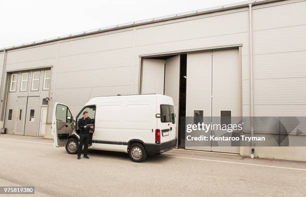 manual worker standing by delivery van on road by industry - delivery truck stock pictures, royalty-free photos & images