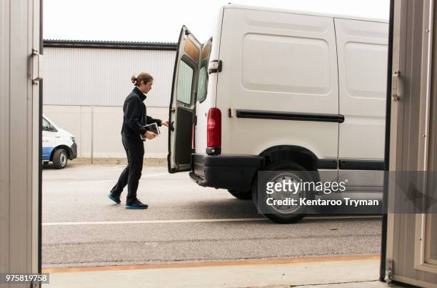 side view of manual worker closing delivery van while standing on road - bestelwagen stockfoto's en -beelden
