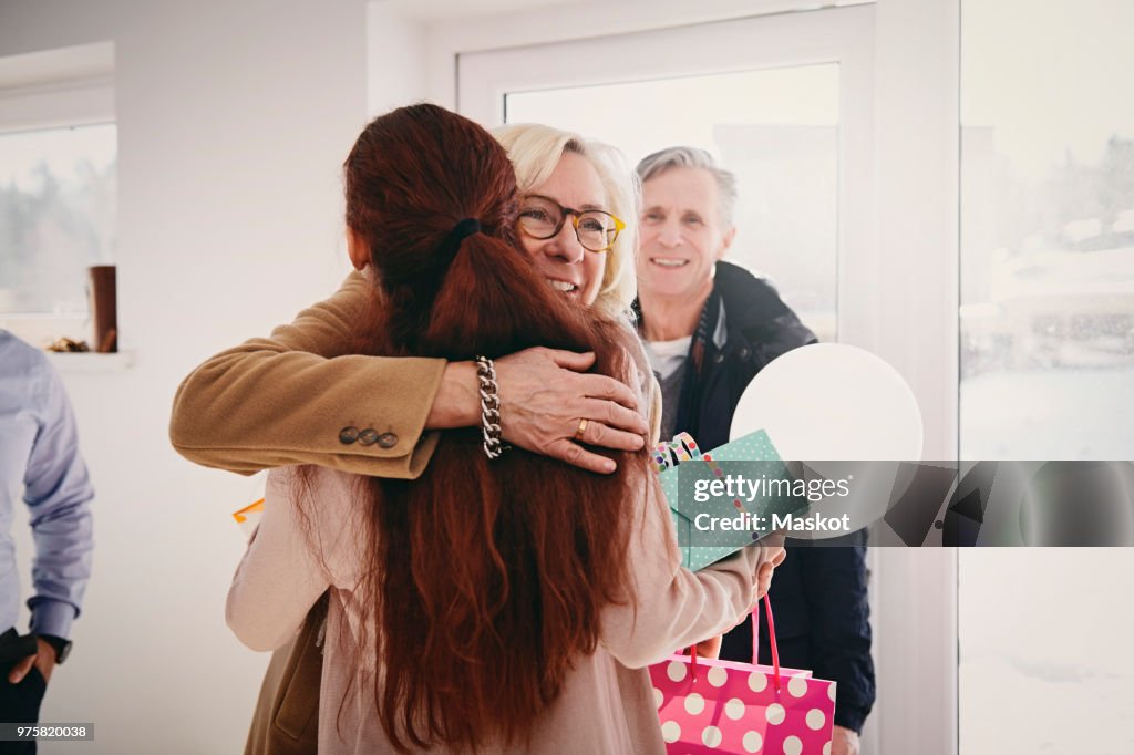 Smiling grandmother embracing granddaughter against door at home