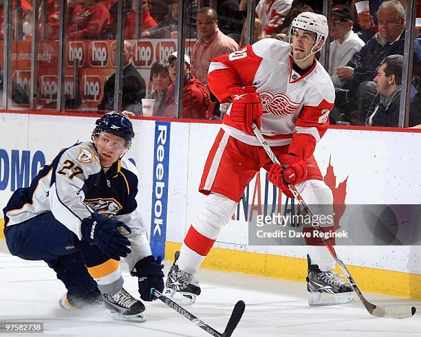 Drew Miller of the Detroit Red Wings passes the puck past Patric Hornqvist of the Nashville Predators during an NHL game at Joe Louis Arena on March...