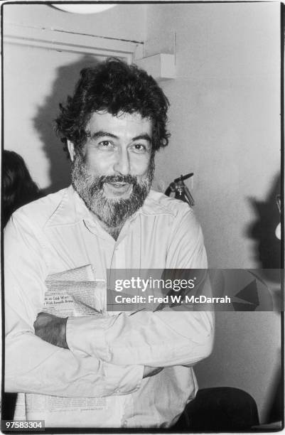 Portrait of American journalist and music critic Nat Hentoff as he stands with his arms folded at an office party for the Village Voice newspaper,...