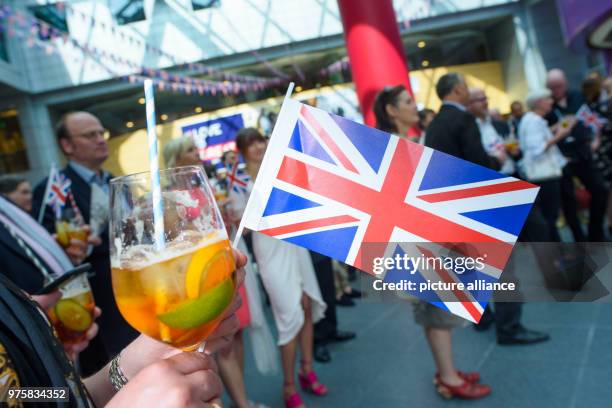 May 2018, Germany, Berlin: A guest caries a glass of the British cocktail Pimms and a British flag during a celebration and live broadcast of the...