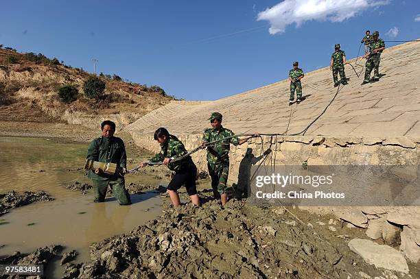 Farmer fetches water from a drying reservoir with the help of militia on March 8, 2010 in Panzhihua of Sichuan Province, China. There was no rainfall...