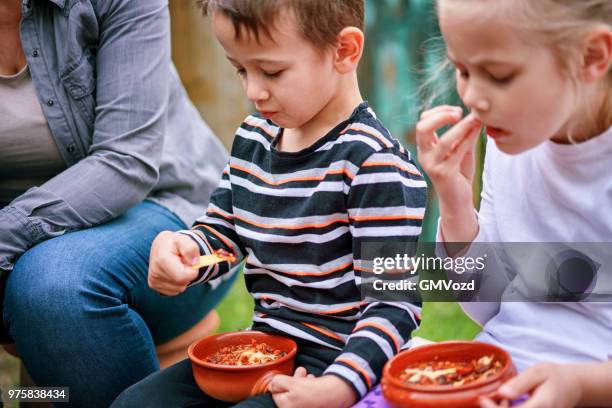 junge familie essen chili con carne vor offenen logfire im außenbereich - carne stock-fotos und bilder