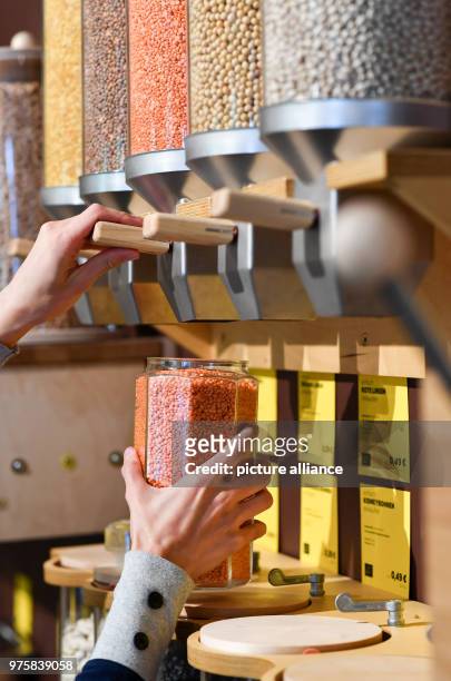 May 2018, Germany, Berlin: A woman fills a glass with lentils at the zero waste shop 'Der Sache wegen - einfach richtig einkaufen' at Lychener...
