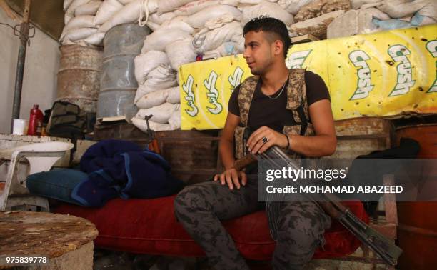 Moawiya Sayasina, the Syrian activist who started scribbling anti-Assad slogans in 2011, sits holding a Kalashnikov assault rifle at a position...