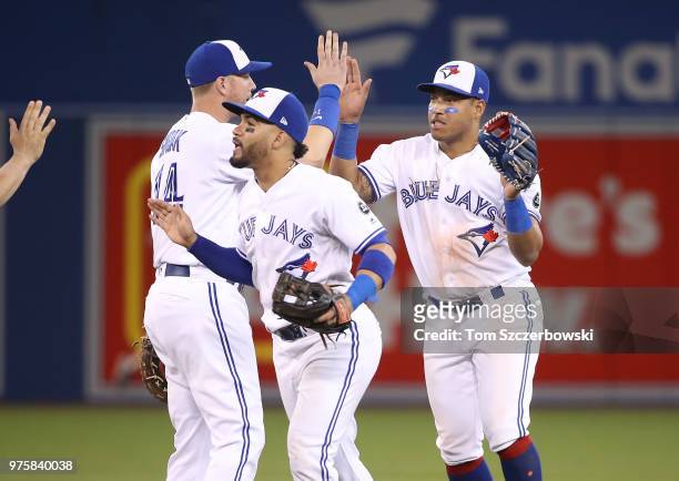 Yangervis Solarte of the Toronto Blue Jays celebrates their victory with Devon Travis and Justin Smoak during MLB game action against the Washington...