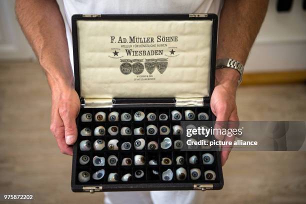 May 2018, Germany, Wiesbaden: Jan Mueller-Uri, manager and ocularist, holding a historical case with ocular protheses made by the company. The...