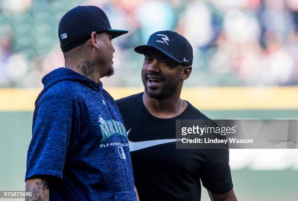 Felix Hernandez of the Seattle Mariners talks with Seattle Seahawks quarterback Russell Wilson after Wilson threw out the ceremonial first pitch...