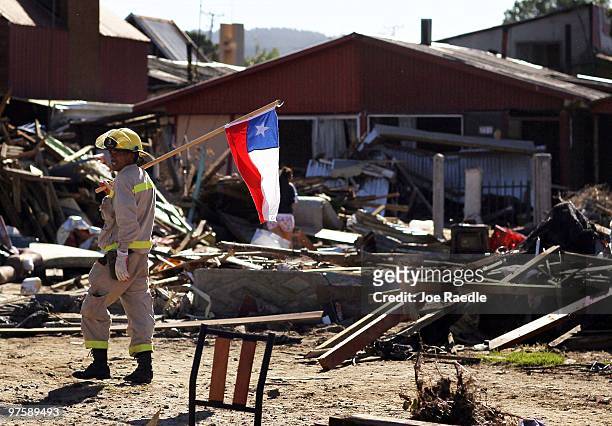 Fireman carries a Chilean flag as he searches for bodies that may be in homes that were destroyed by the February 27th earthquake and following...