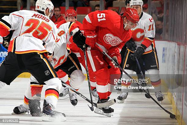 Valtteri Filppula of the Detroit Red Wings tries to get the puck out of the boards and keep it away from David Moss and Niklas Hagman of the Calgary...