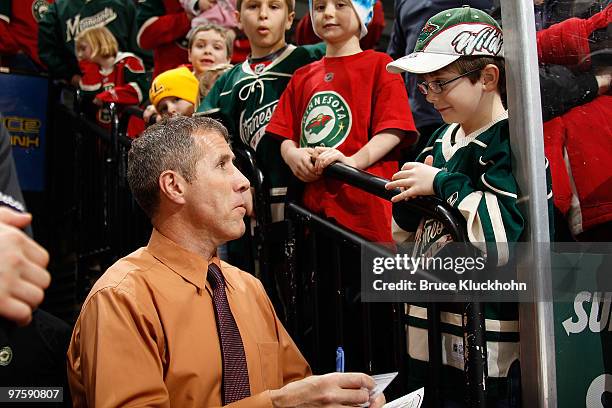 Assistant coach Dave Barr of the Minnesota Wild signs a young fan's card prior to the game against the Florida Panthers at the Xcel Energy Center on...