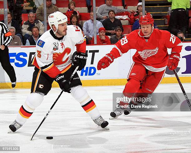 Ian White of the Calgary Flames tries to keep control of the puck away from Jason Williams of the Detroit Red Wings during an NHL game at Joe Louis...