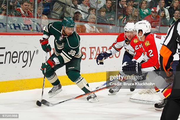 Robbie Earl of the Minnesota Wild battles for possession of the puck with Kamil Kreps and Keith Ballard of the Florida Panthers during the game at...