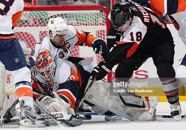 Dwayne Roloson and Doug Weight of the New York Islanders defend against the attack of Mike Richards of the Philadelphia Flyers on March 9, 2010 at...
