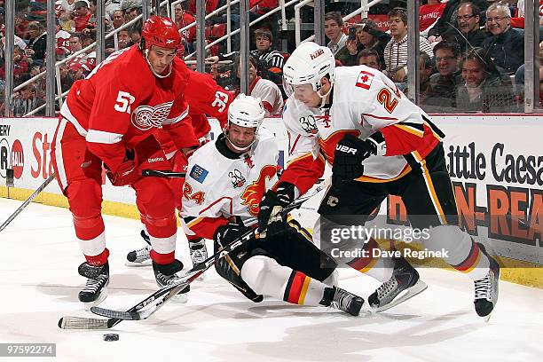 Craig Conroy of the Calgary Flames slides for the loose puck as teammate David Moss and Jonathan Ericsson of the Detroit Red Wings also battle for...