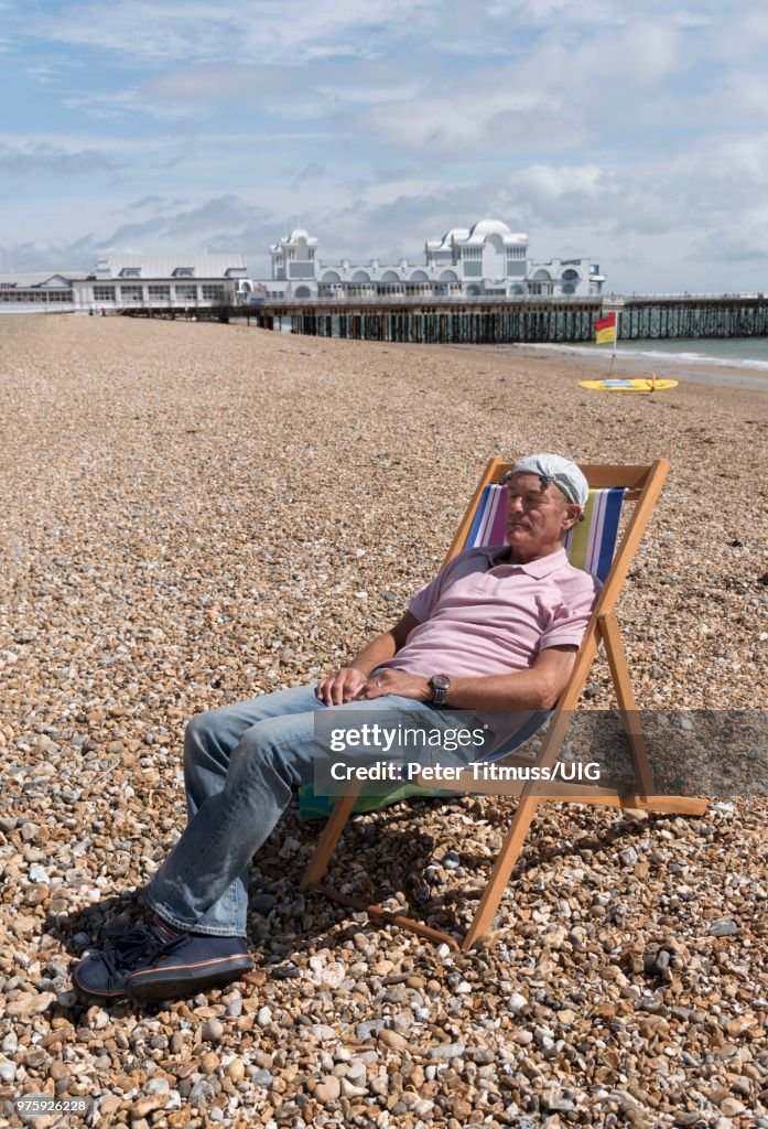 Elderly man wearing a knotted handkerchief on his head relaxing on the beach