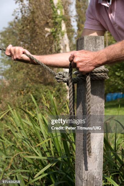 mooring line being attached to a post with a round turn and two half hitches knot - anlegetau stock-fotos und bilder