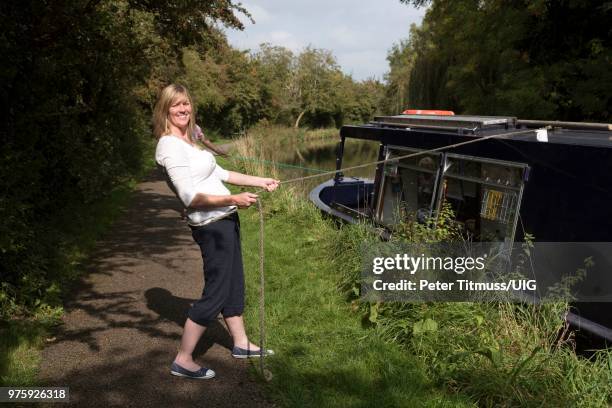 woman pulling the mooring line of a narrow boat - anlegetau stock-fotos und bilder