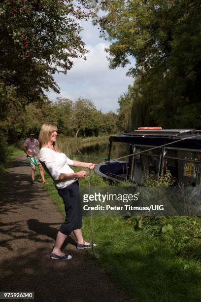 woman pulling the mooring line of a narrow boat - anlegetau stock-fotos und bilder