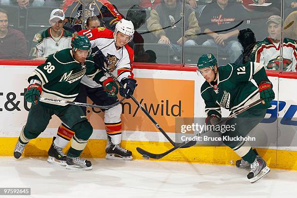 Robbie Earl and Chuck Kobasew of the Minnesota Wild battle for a loose puck with David Booth of the Florida Panthers during the game at the Xcel...