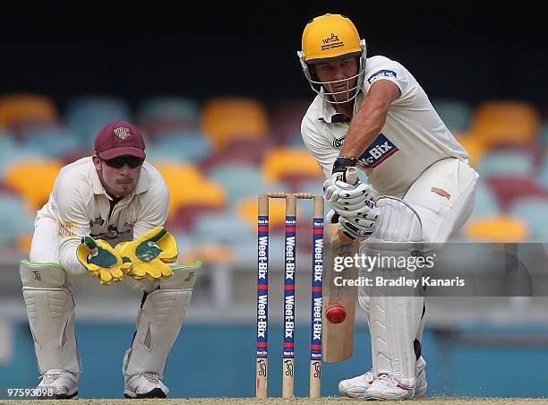 Michael Swart of the Warriors plays a defensive shot, whilst Chris Hartley keeps during the Sheffield Shield match between the Queensland Bulls and...