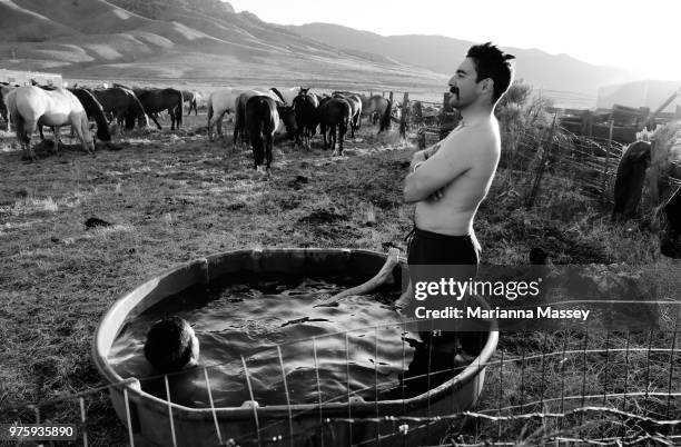 Wranglers cool off and wash off the days dirt in a cold horse trough at camp on June 12, 2018 in Reno, Nevada. The Reno Rodeo Cattle Drive celebrates...