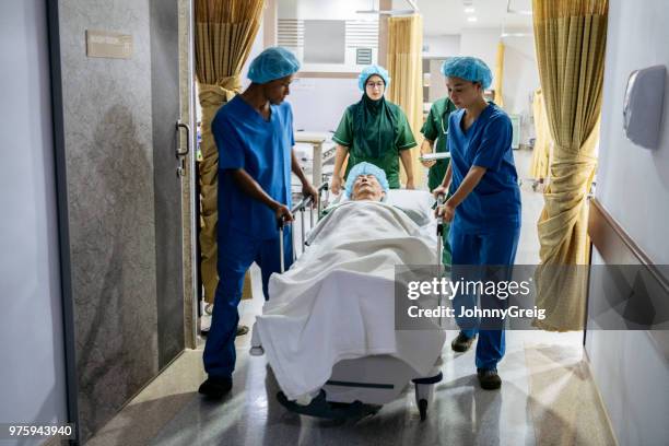 medical team pushing hospital bed down corridor - critical illness stock pictures, royalty-free photos & images