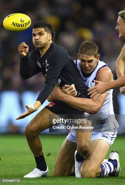 Sam Petrevski-Seton of the Blues handballs whilst being tackled by Aaron Sandilands of the Dockers during the round 13 AFL match between the Carlton...