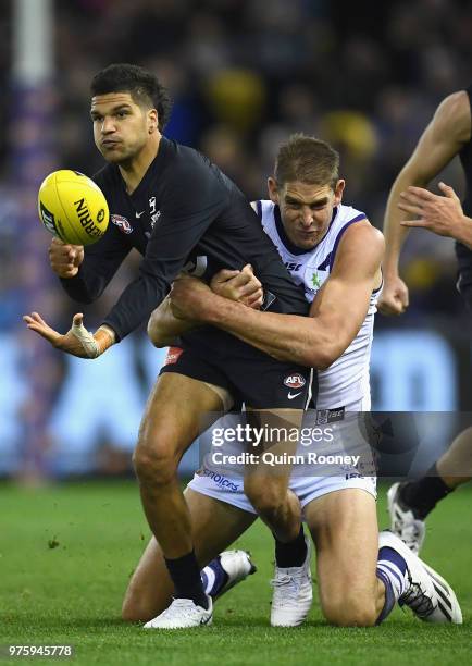 Sam Petrevski-Seton of the Blues handballs whilst being tackled by Aaron Sandilands of the Dockers during the round 13 AFL match between the Carlton...